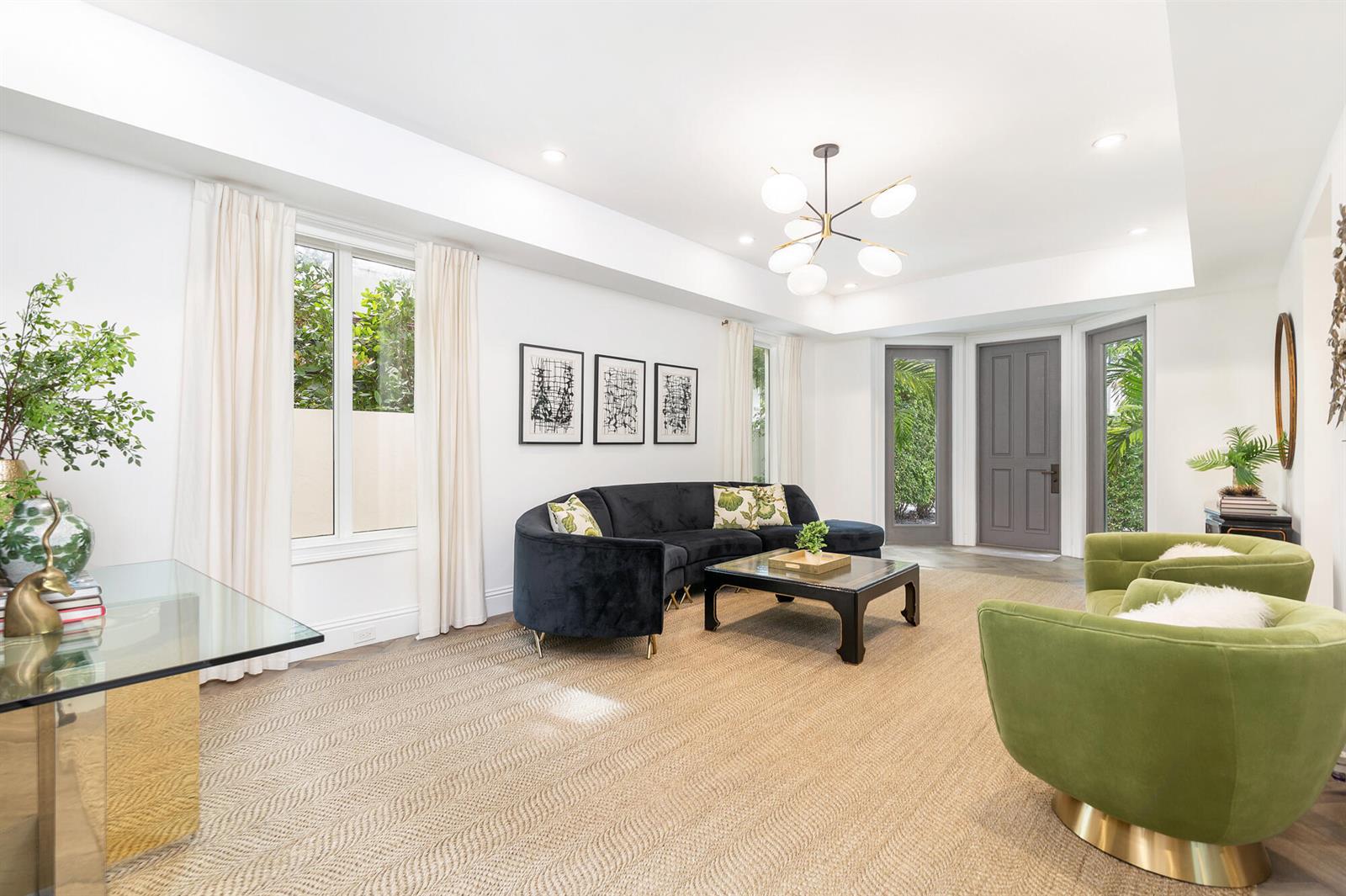 A bright living room features a dark curved sofa, green armchairs, and a glass coffee table — 443 Seaview Avenue, Palm Beach FL 33480, PALM BEACH, FL