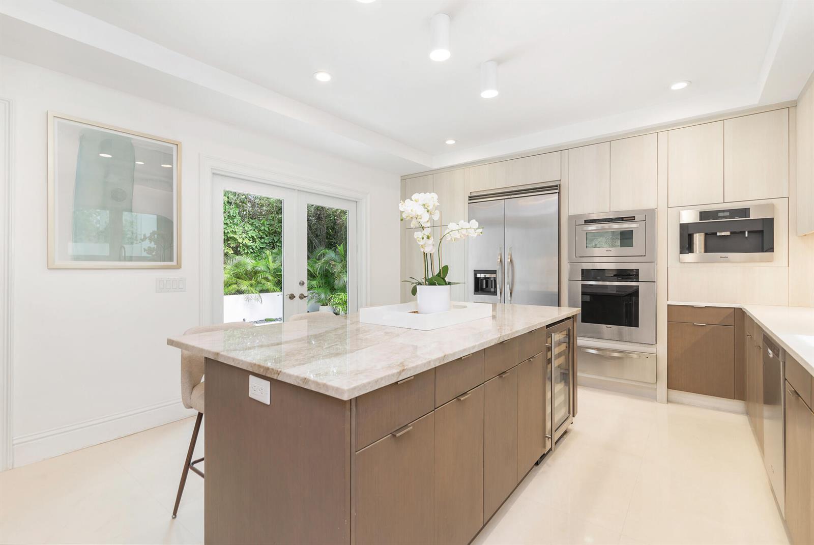 A modern kitchen features a stone-topped island, stainless steel appliances, and light wood cabinetry — 443 Seaview Avenue, Palm Beach FL 33480, PALM BEACH, FL