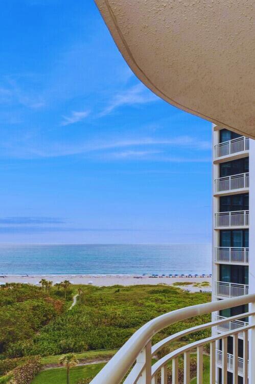 A high-angle view from a balcony overlooking a beach, ocean, and a neighboring high-rise building — 3000 N Ocean Drive # A, Singer Island FL 33404, SINGER ISLAND, FL