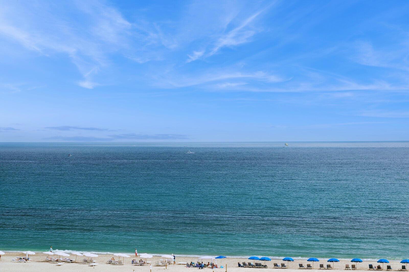 A high-angle view of a sandy beach with rows of umbrellas and the ocean beyond — 3000 N Ocean Drive # A, Singer Island FL 33404, SINGER ISLAND, FL