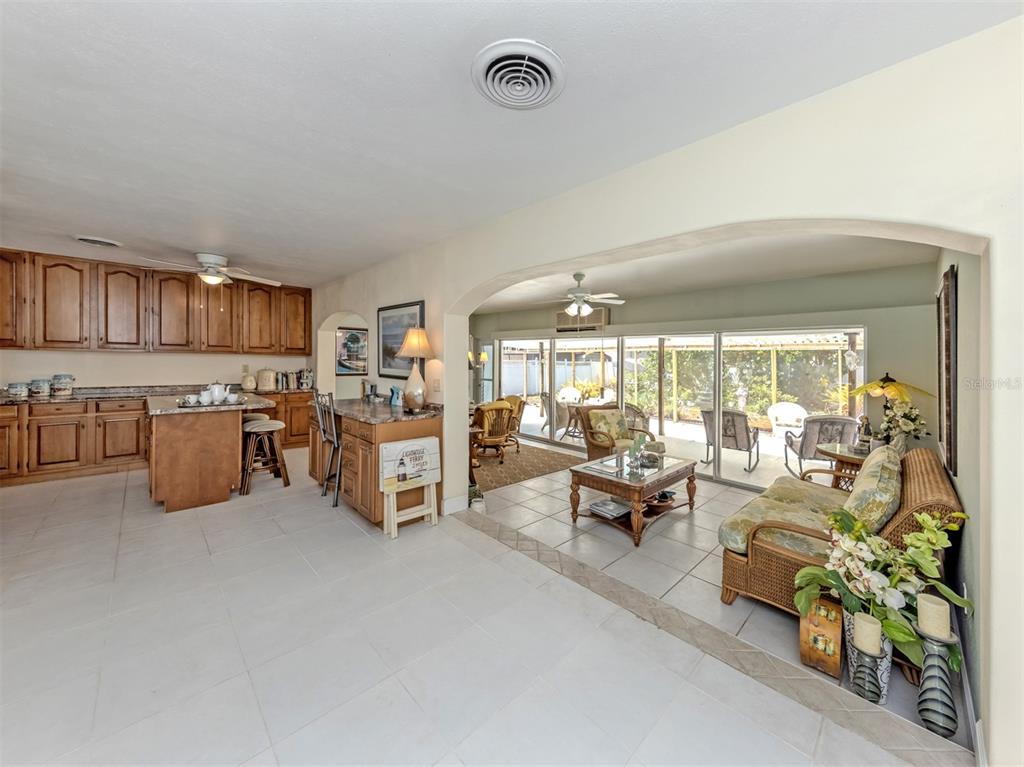 A kitchen with wood cabinets opens into a sunroom with tile floors and sliding doors — 814 GUILD DRIVE, VENICE, FL