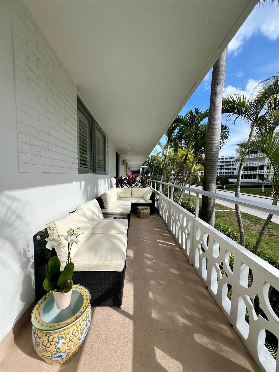 A long balcony features outdoor wicker seating, a decorative ceramic side table, and palm trees — 139 Sunrise Avenue # 204, Palm Beach FL 33480, PALM BEACH, FL