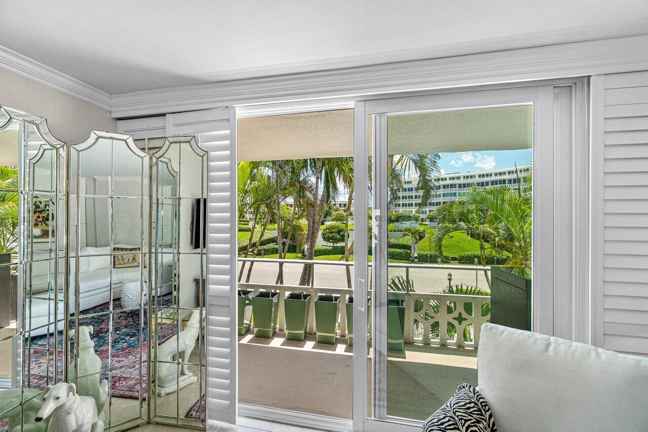 A living room with a mirrored folding screen and sliding glass doors opening to a balcony — 139 Sunrise Avenue # 204, Palm Beach FL 33480, PALM BEACH, FL
