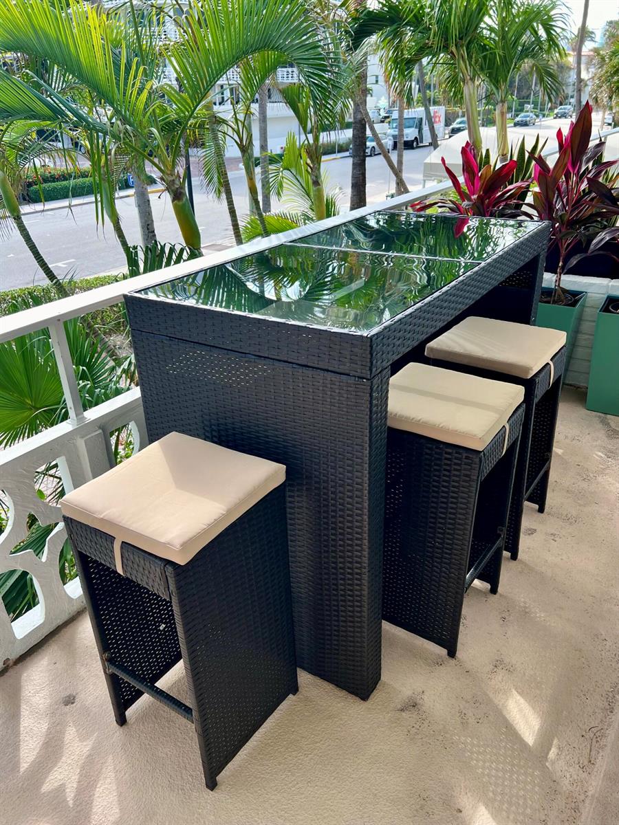 A black wicker bar set with a glass top and three stools sits on a balcony — 139 Sunrise Avenue # 204, Palm Beach FL 33480, PALM BEACH, FL