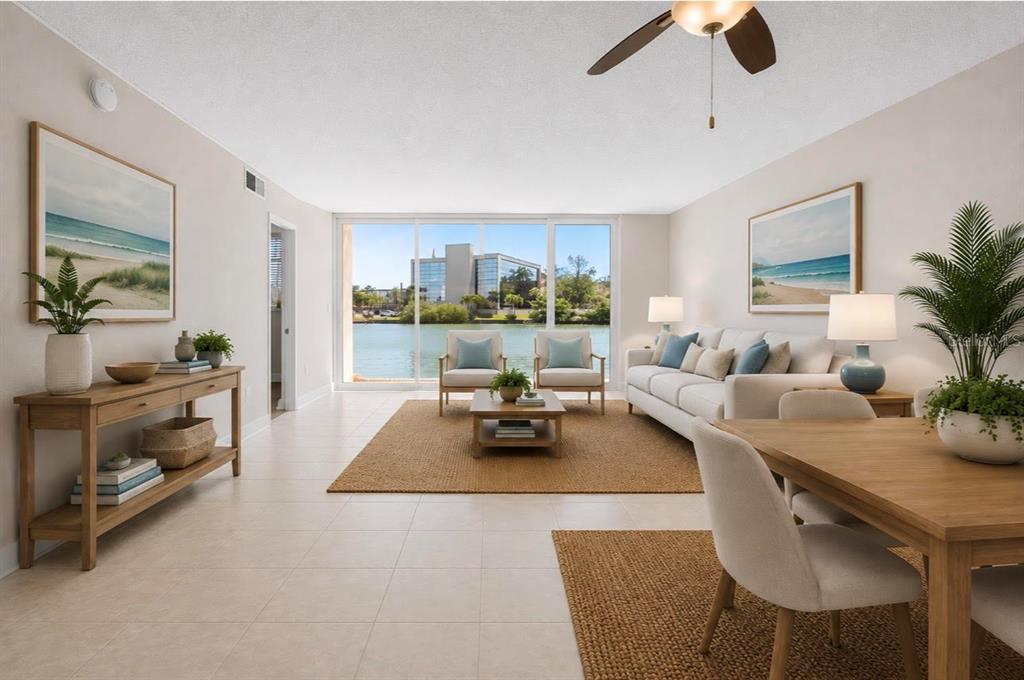 This is a digitally staged living room with tile floors, a dining area, and water views — 7425 BAY ISLAND DRIVE S UNIT 104, SOUTH PASADENA, FL