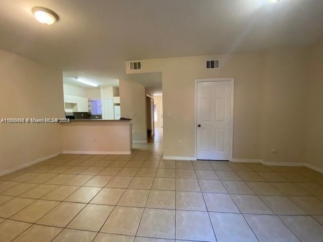 A hallway with beige tile flooring leads to a glass door opening to the outdoors — 646 SW 7th Ter, Florida City FL 33034, FLORIDA CITY, FL