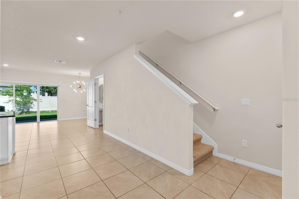 A tiled room features a staircase with carpeted steps and a sliding glass door — 12460 BOWES BRANCH ROAD, ORLANDO, FL
