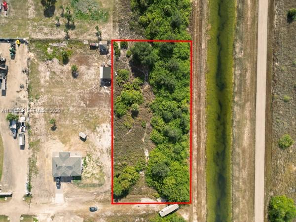 An aerial view shows a rectangular, tree-covered vacant lot outlined in red next to a canal — 7969 13TH TER, La Belle FL 33935, LA BELLE, FL