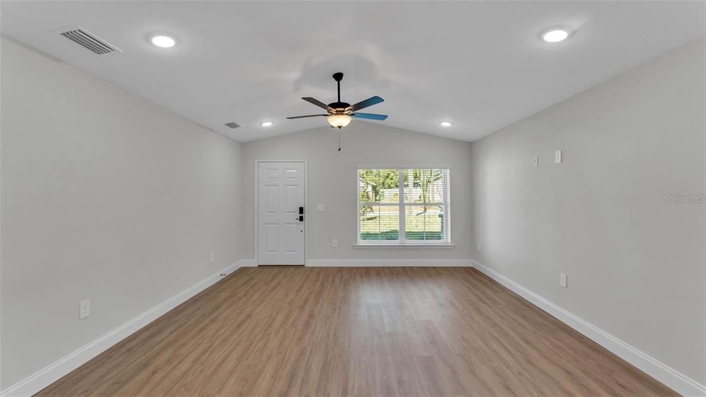 A living room with light gray walls, wood-look flooring, a vaulted ceiling, and a ceiling fan — 1246 DOROTHY STREET, LAKELAND, FL