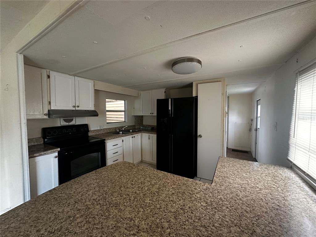 A kitchen features white cabinets, black appliances, and speckled laminate countertops — 324 TRAILORAMA DRIVE, NORTH PORT, FL