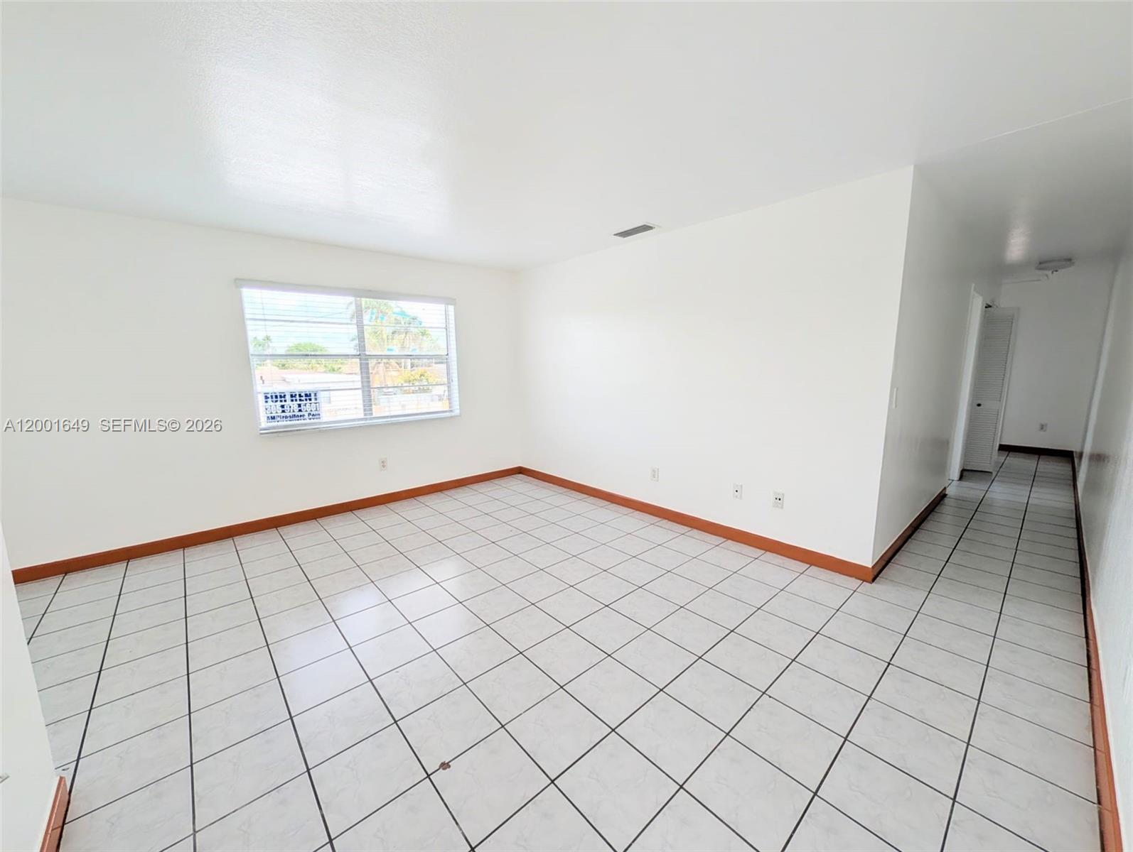 An empty room with white walls, tiled floors, and a window overlooking a street — 1551 NE 8th St # 8, Homestead FL 33033, HOMESTEAD, FL