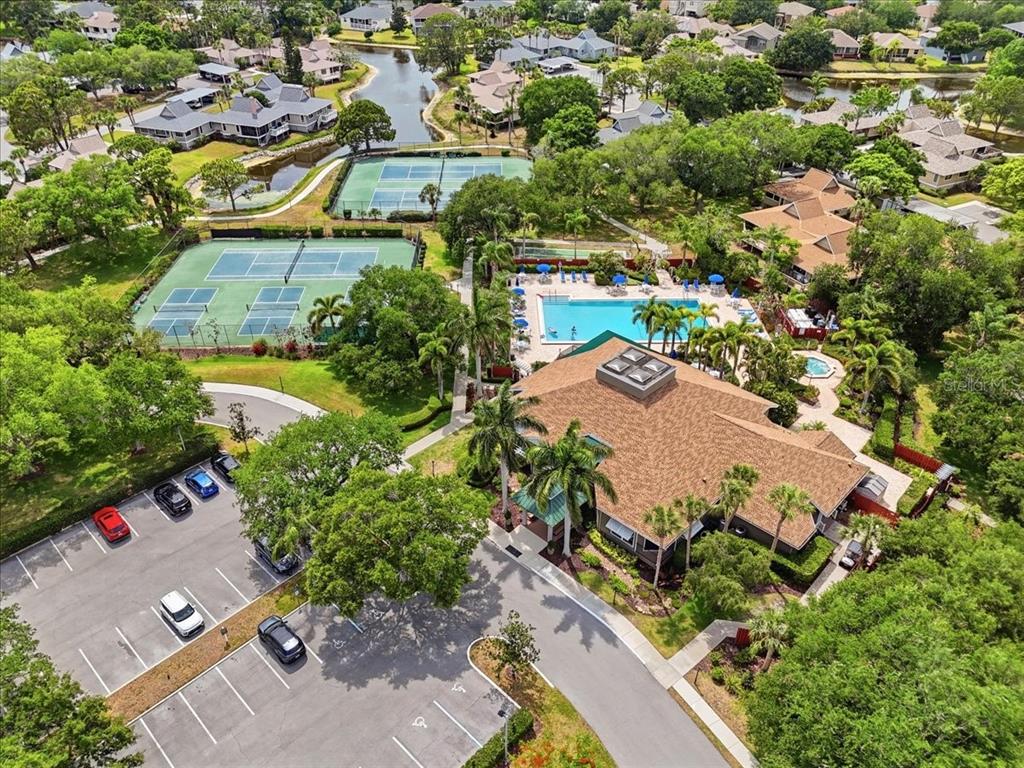 An aerial view of a community clubhouse featuring a swimming pool and tennis courts — 992 SPINNAKER COURT, TARPON SPRINGS, FL