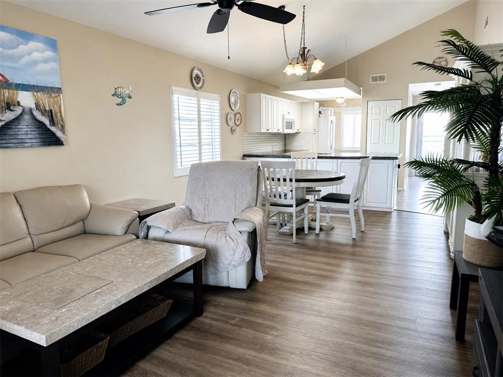 This open-concept living and dining area features light-colored walls, wood-look flooring, and white cabinetry — 6800 PLACIDA ROAD UNIT 257, ENGLEWOOD, FL