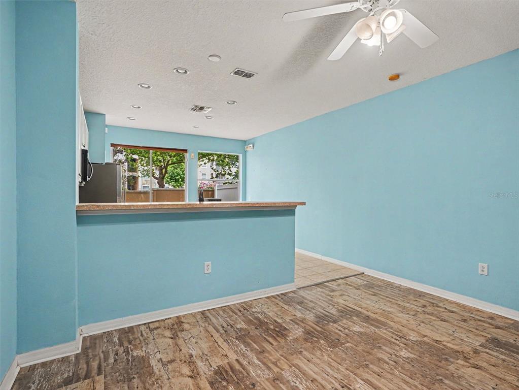 A room with light blue walls, wood-look flooring, a breakfast bar, and a ceiling fan — 7631 LONG ISLAND DR, KISSIMMEE, FL