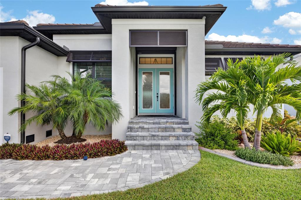 A single-story house with a two-car garage and a teal front door at sunset — 15872 MELPORT CIRCLE, PORT CHARLOTTE, FL