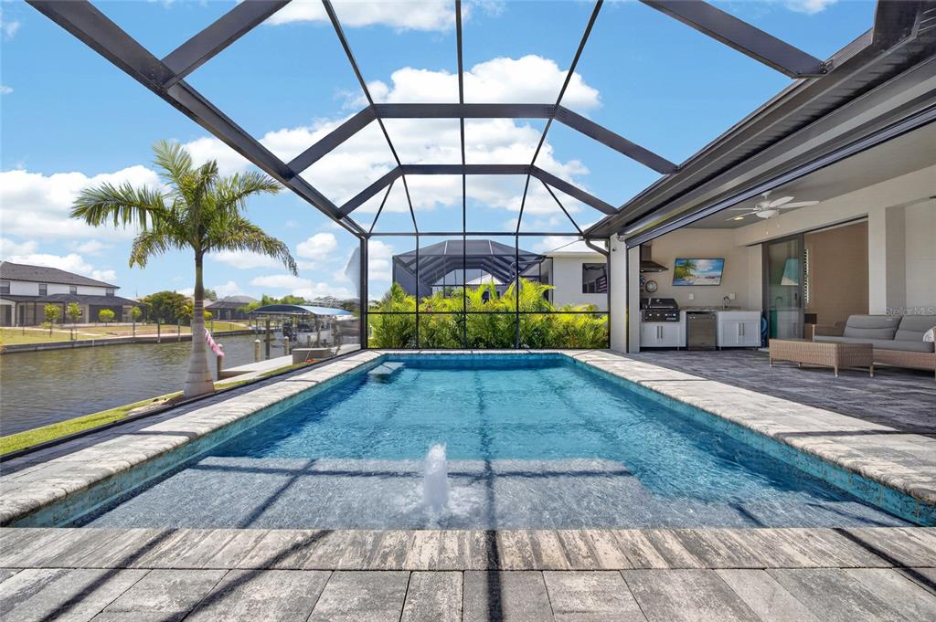 A foyer with wood-look flooring, double glass-paneled doors, a modern chandelier, and a dark wet bar — 15872 MELPORT CIRCLE, PORT CHARLOTTE, FL