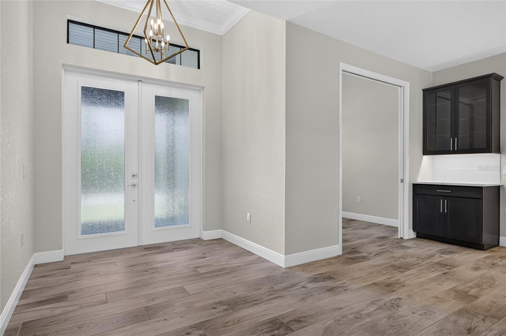 An open-concept living room and kitchen with wood-look flooring, a tray ceiling, and sliding doors — 15872 MELPORT CIRCLE, PORT CHARLOTTE, FL