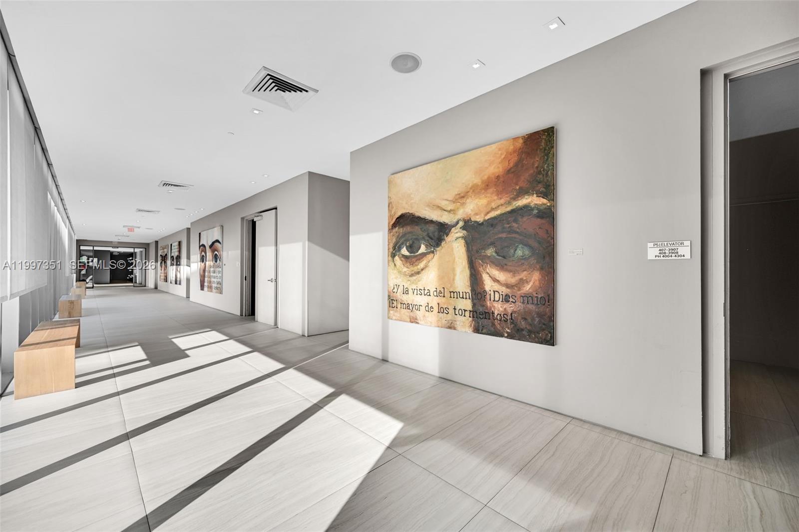 A modern hallway features light tile flooring, recessed lighting, and large portrait paintings on walls — 460 NE 28th St # 2908, Miami FL 33137, MIAMI, FL