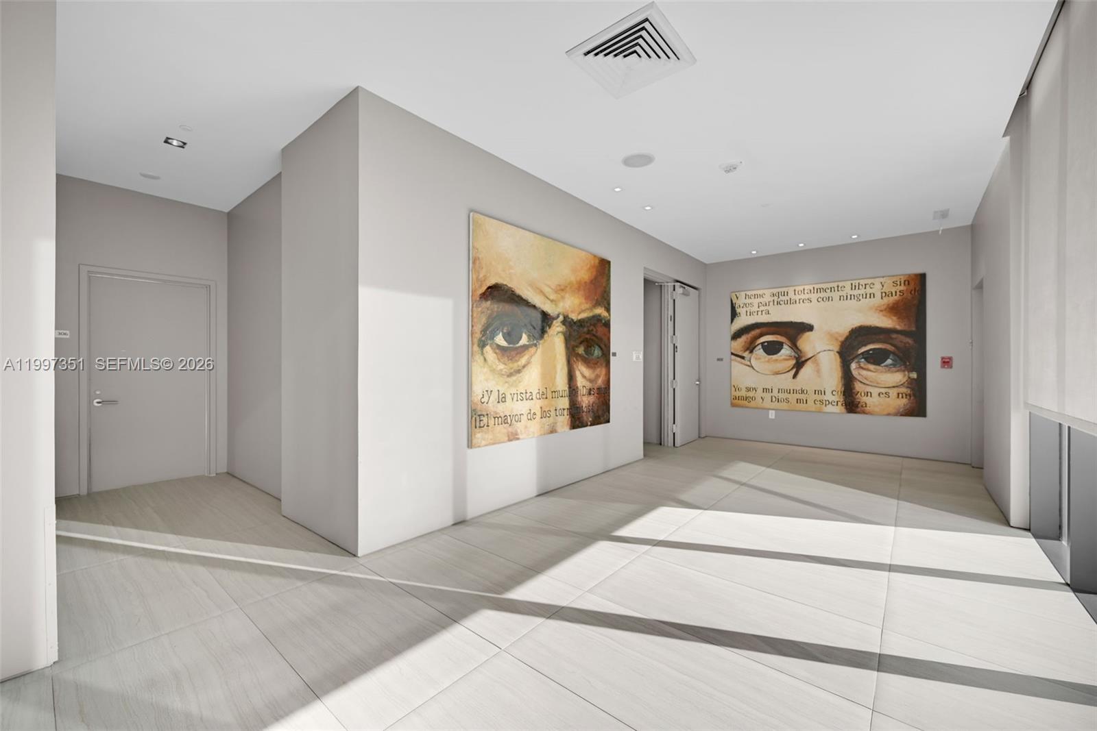 A minimalist hallway features light tile flooring, recessed lighting, and two large portraits on the walls — 460 NE 28th St # 2908, Miami FL 33137, MIAMI, FL