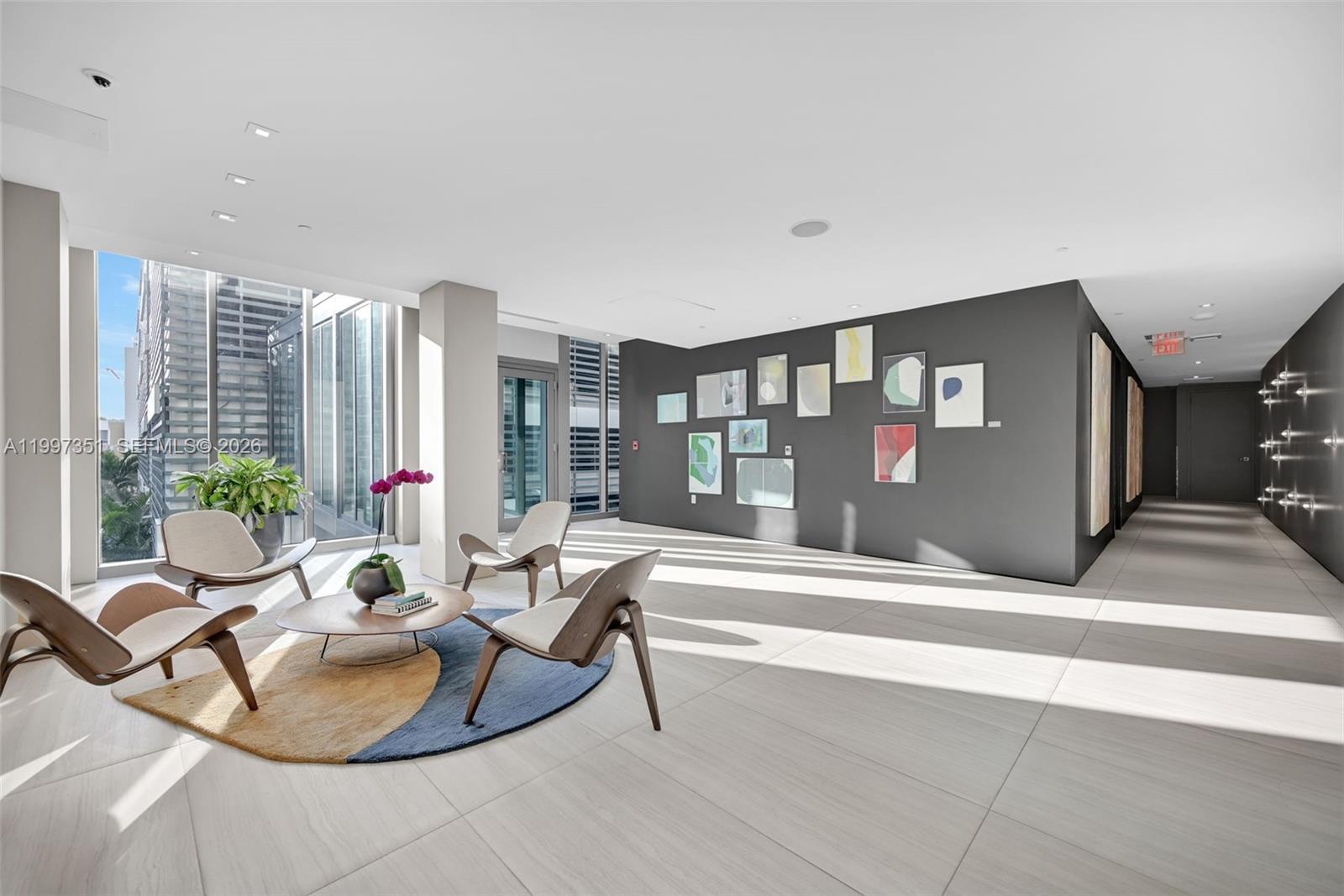 A modern lounge area features mid-century chairs, a circular rug, and an art-filled gray wall — 460 NE 28th St # 2908, Miami FL 33137, MIAMI, FL