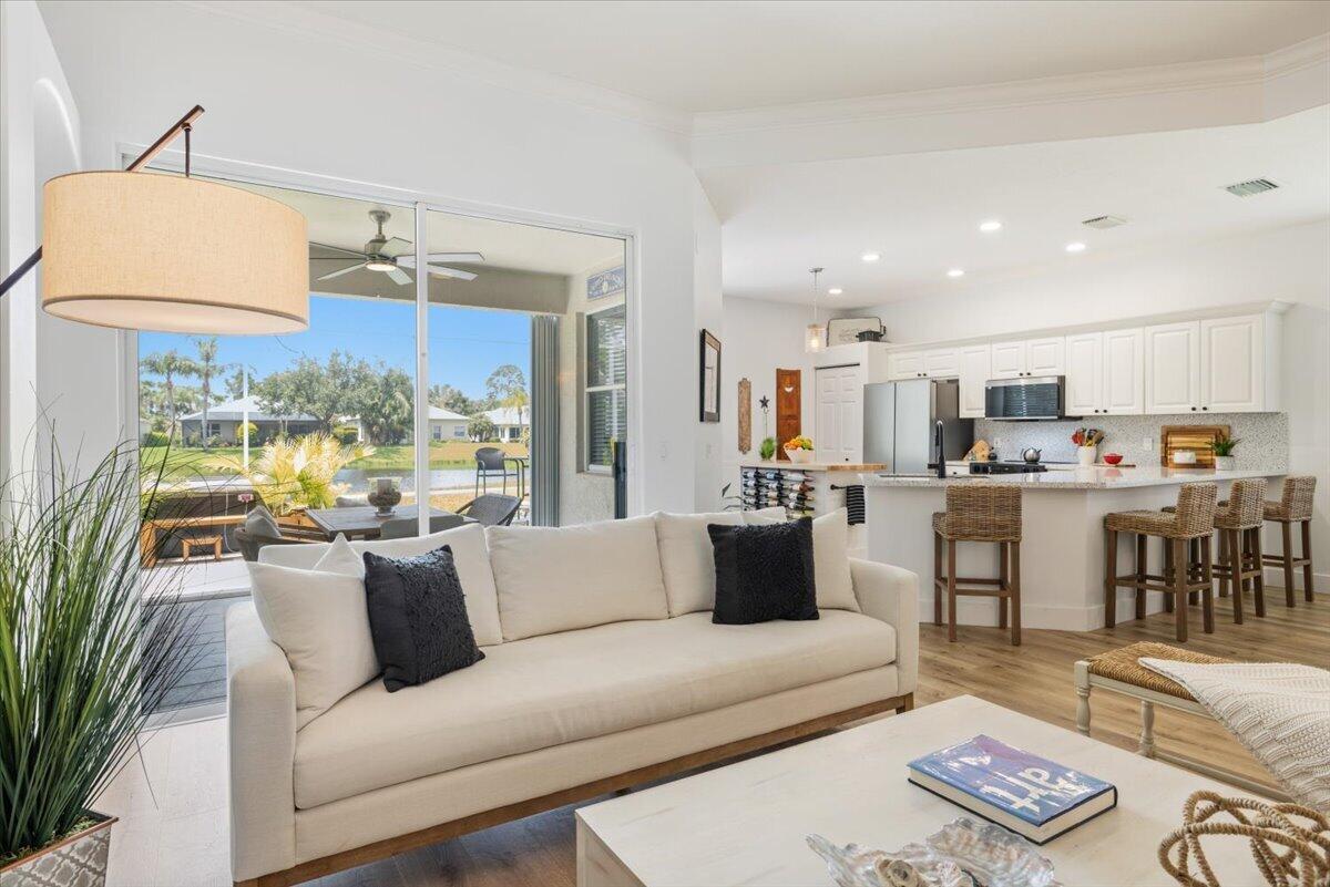 A living room with a white sofa overlooks a patio and canal through sliding doors — 6265 33rd Manor, Vero Beach FL 32966, VERO BEACH, FL
