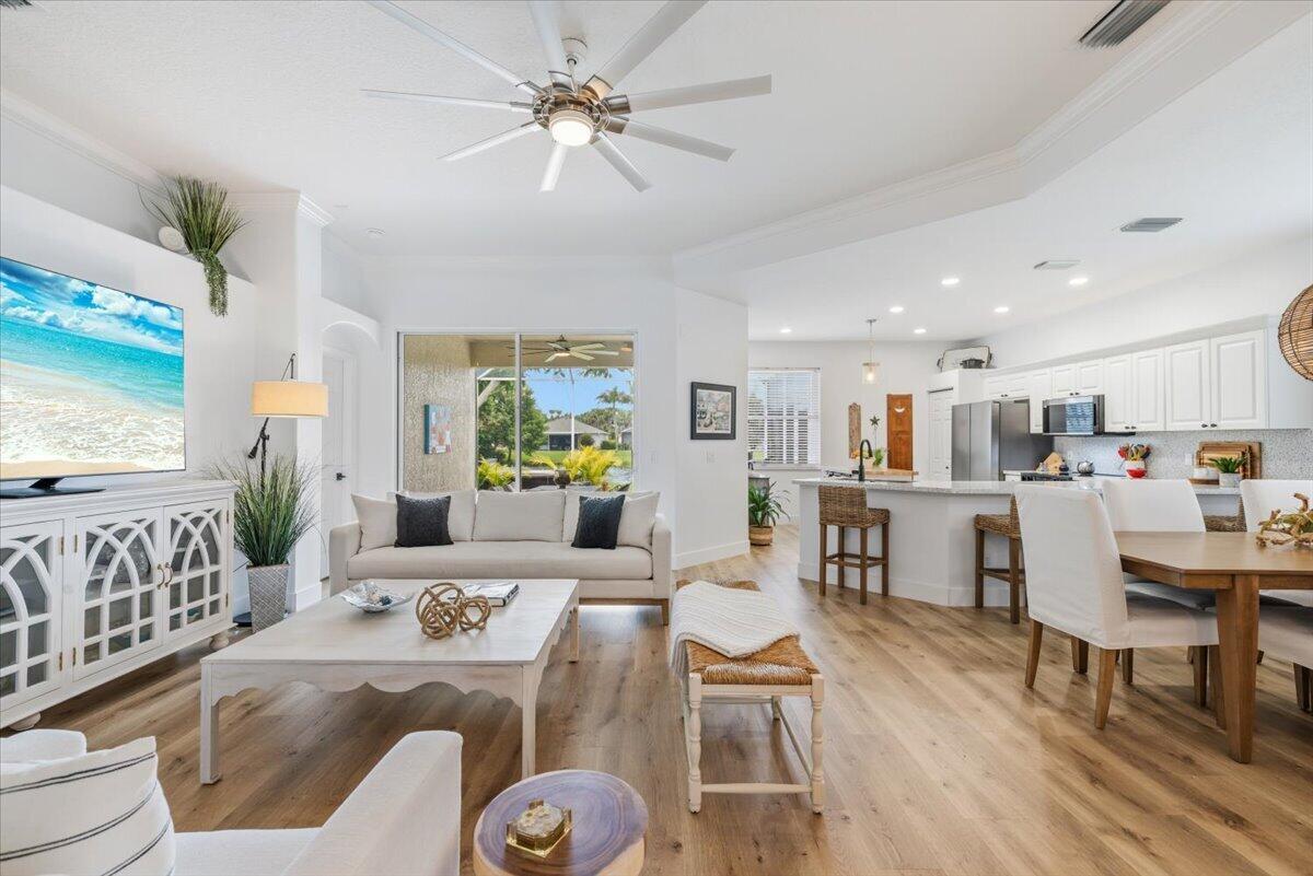 An open-concept living room and kitchen featuring light wood floors and white cabinetry — 6265 33rd Manor, Vero Beach FL 32966, VERO BEACH, FL