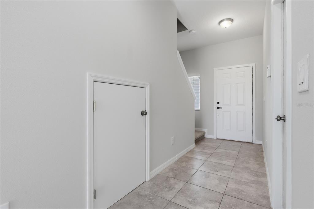 A tiled entryway features a white front door, a small storage door, and stairs — 7005 GRAND ELM DRIVE, RIVERVIEW, FL