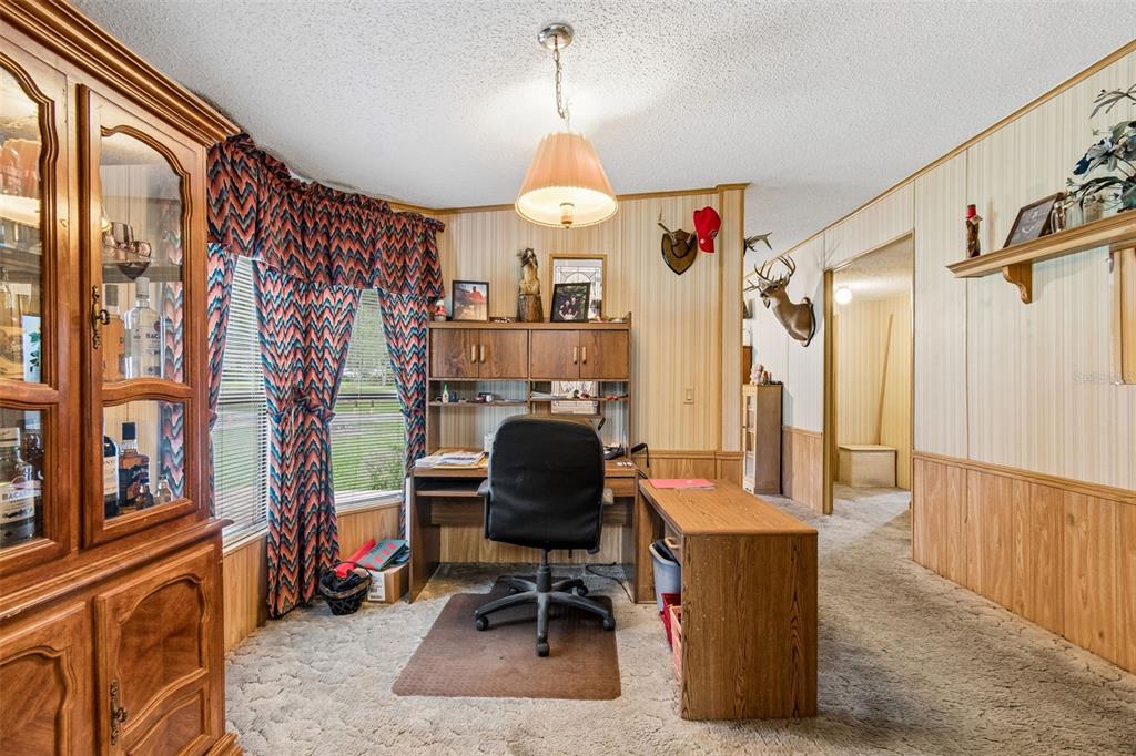 A home office features wood-paneled walls, a desk, a swivel chair, and taxidermy deer mounts — 6325 OAKVIEW LANE, LAKELAND, FL