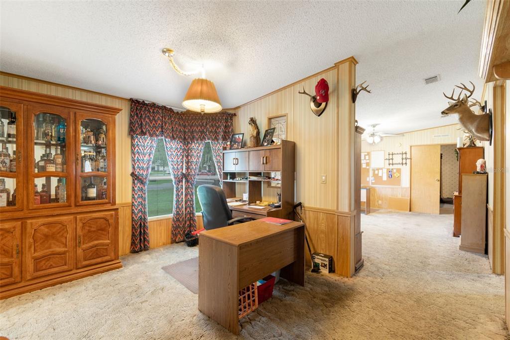 A home office features wood paneling, a desk, a hutch, and a mounted deer head — 6325 OAKVIEW LANE, LAKELAND, FL