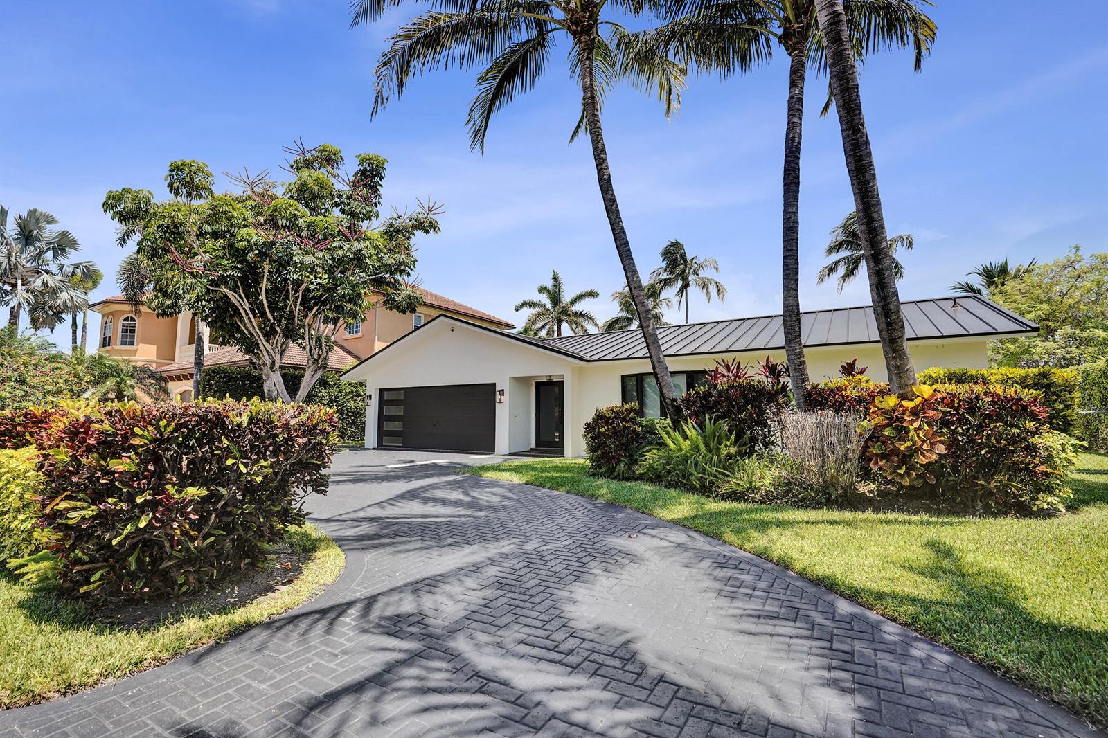A single-story house with a dark metal roof and a herringbone-patterned paved driveway — 933 Banyan Drive, Delray Beach FL 33483, DELRAY BEACH, FL