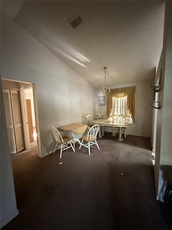 A dining area features a vaulted ceiling, carpeted flooring, and two wooden dining sets — 1231 GAGE AVENUE, DELTONA, FL