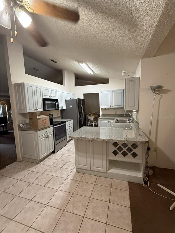 A kitchen features white cabinets, granite countertops, tile flooring, and a breakfast bar — 1231 GAGE AVENUE, DELTONA, FL