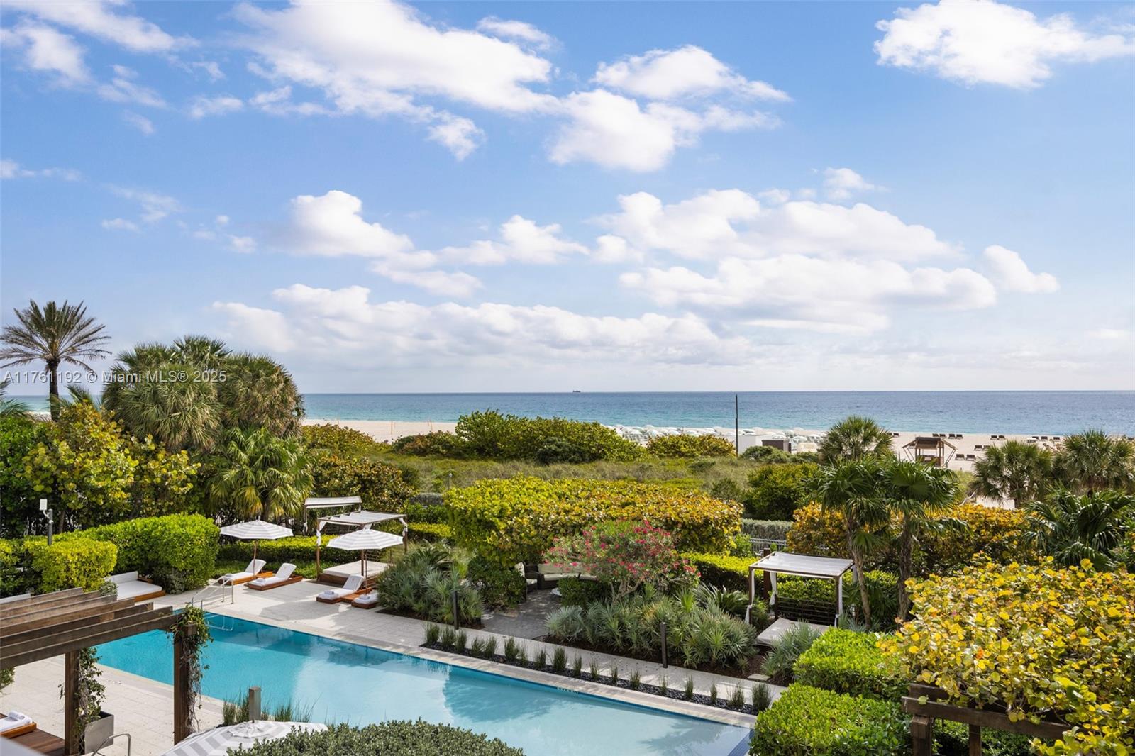 An outdoor swimming pool is surrounded by lush landscaping and lounge chairs near the beach — 125 Ocean Dr # 0303, Miami Beach FL 33139, MIAMI BEACH, FL