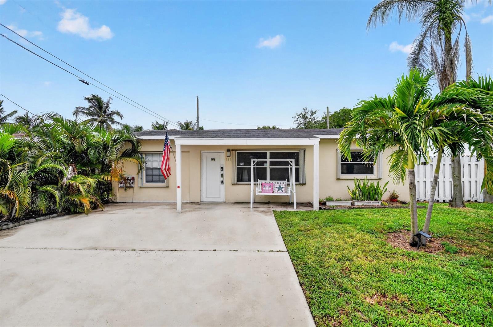 A single-story house with a concrete driveway, a front porch swing, and tropical landscaping — 512 SE 1st Street, Boynton Beach FL 33435, BOYNTON BEACH, FL