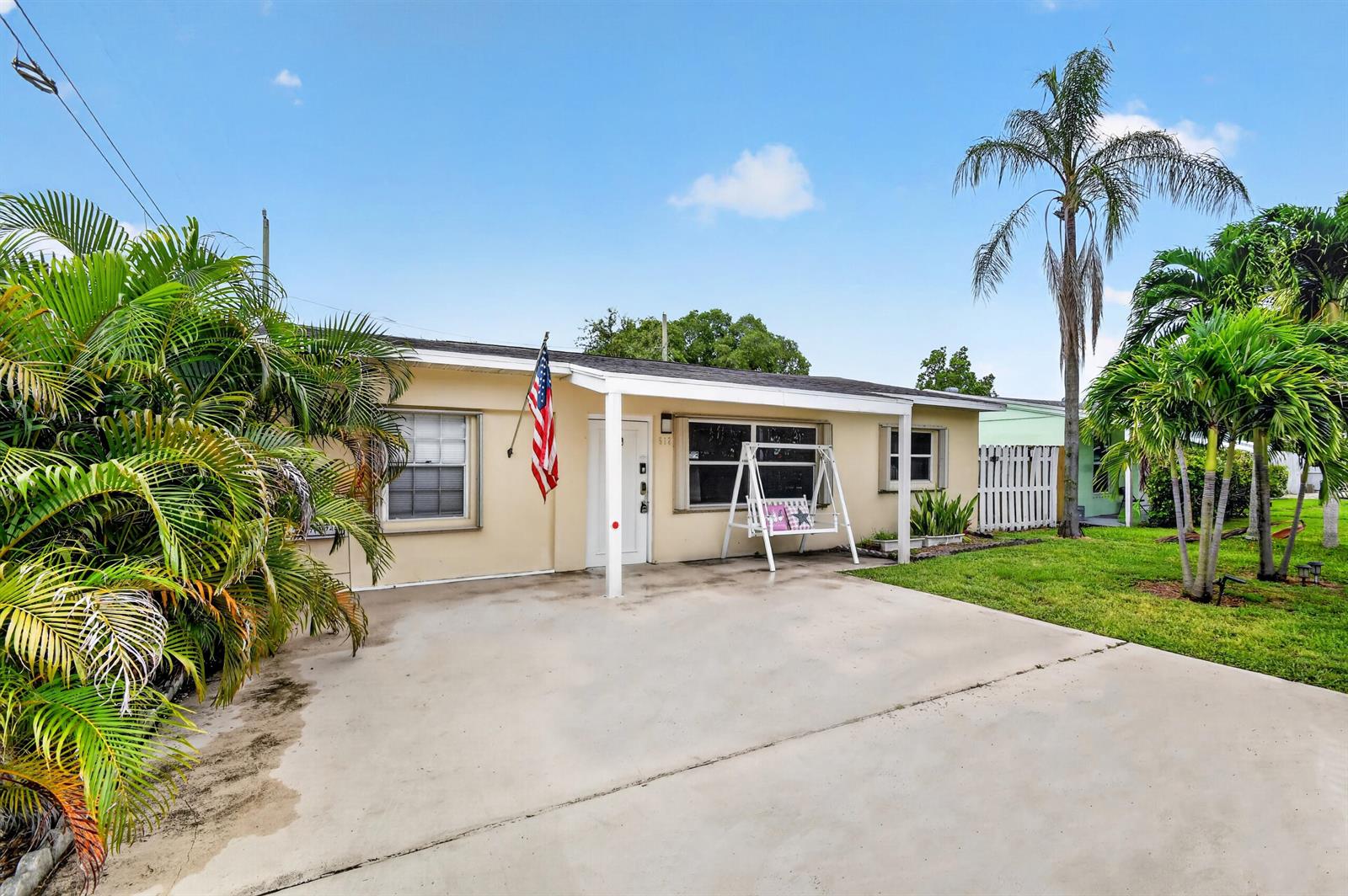A single-story house with a concrete driveway, a front porch swing, and palm trees — 512 SE 1st Street, Boynton Beach FL 33435, BOYNTON BEACH, FL