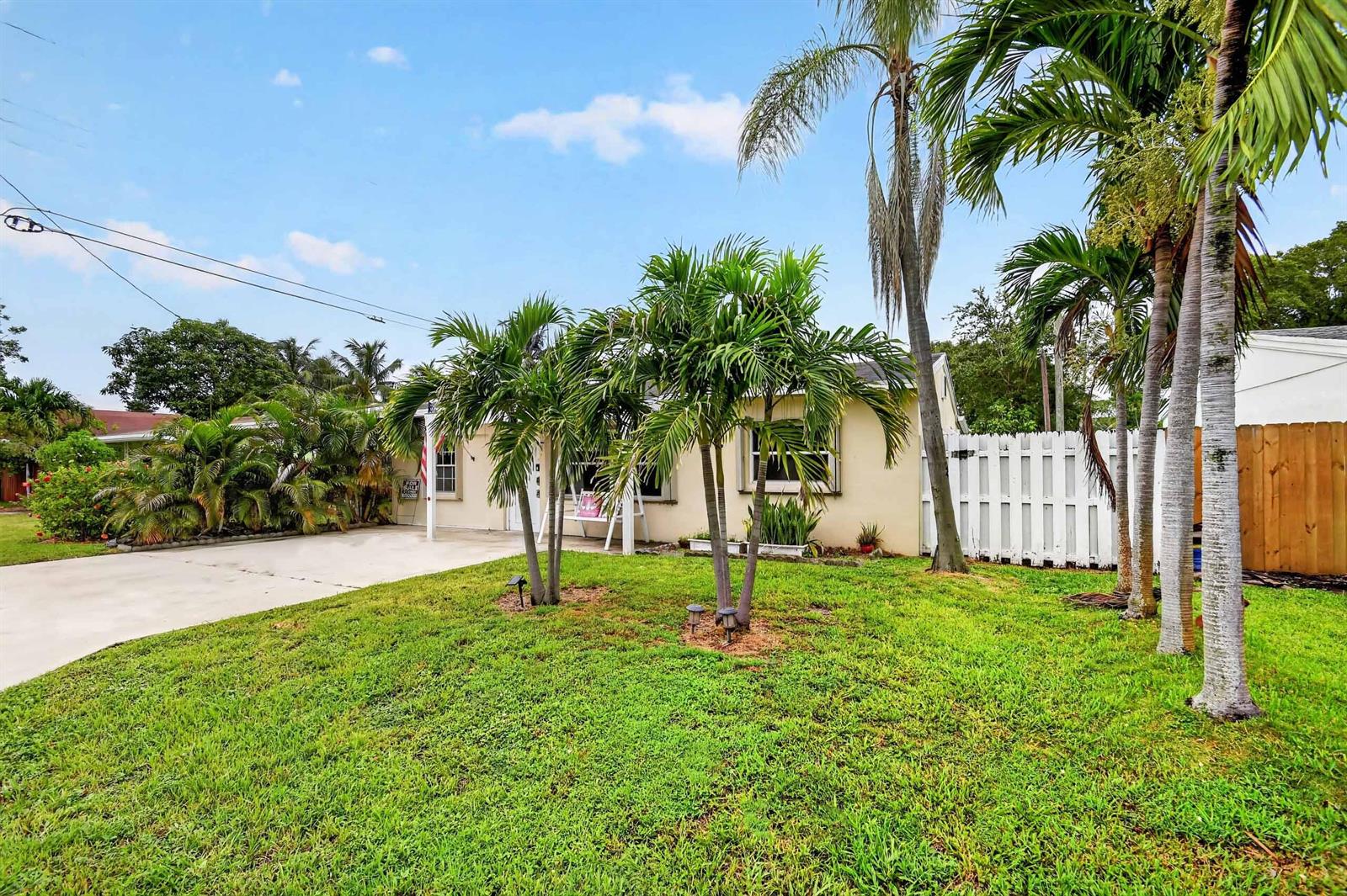 A single-story house with a concrete driveway, palm trees, and a white fence — 512 SE 1st Street, Boynton Beach FL 33435, BOYNTON BEACH, FL
