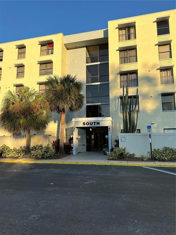 The exterior of a multi-story apartment building features a central entrance labeled South — 701 S MADISON AVENUE UNIT 410, CLEARWATER, FL