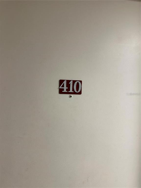 A white door features a red sign with the number 410 and a peephole — 701 S MADISON AVENUE UNIT 410, CLEARWATER, FL