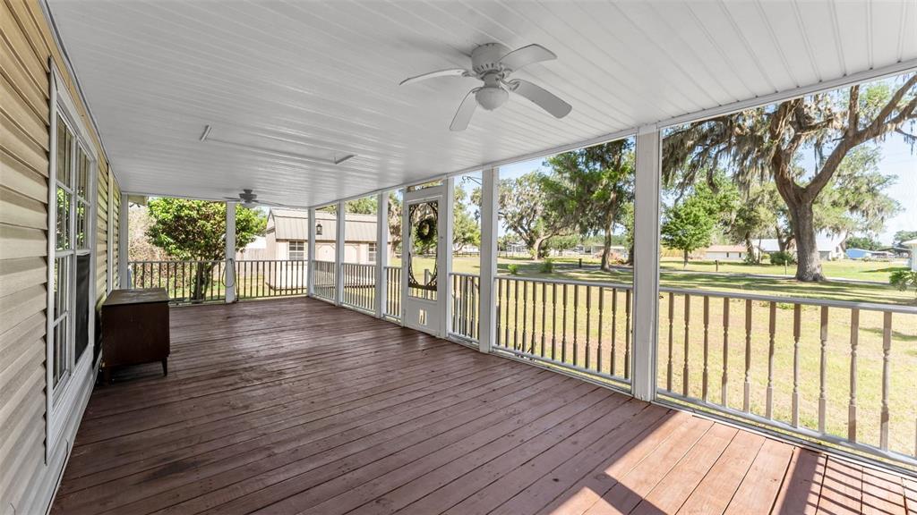 A covered wooden porch features a ceiling fan, white railings, and a view of trees — 501 SWILLEY ROAD, PLANT CITY, FL