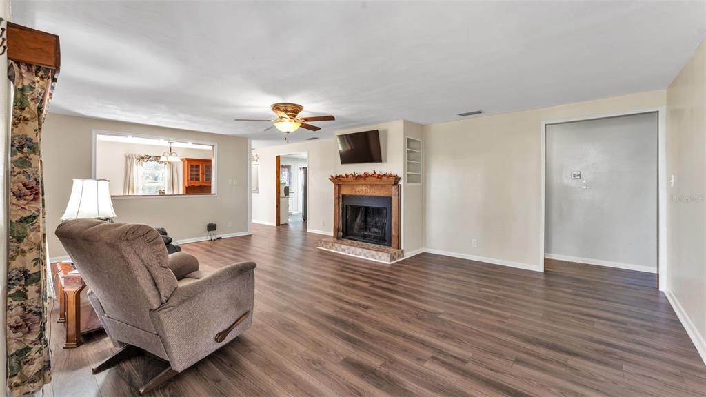 A living room features wood-look flooring, a fireplace with a mantel, and a ceiling fan — 501 SWILLEY ROAD, PLANT CITY, FL