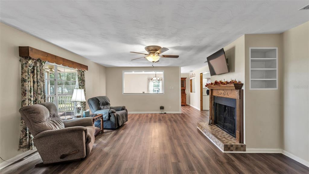A living room features wood-look flooring, a fireplace, a ceiling fan, and two armchairs — 501 SWILLEY ROAD, PLANT CITY, FL