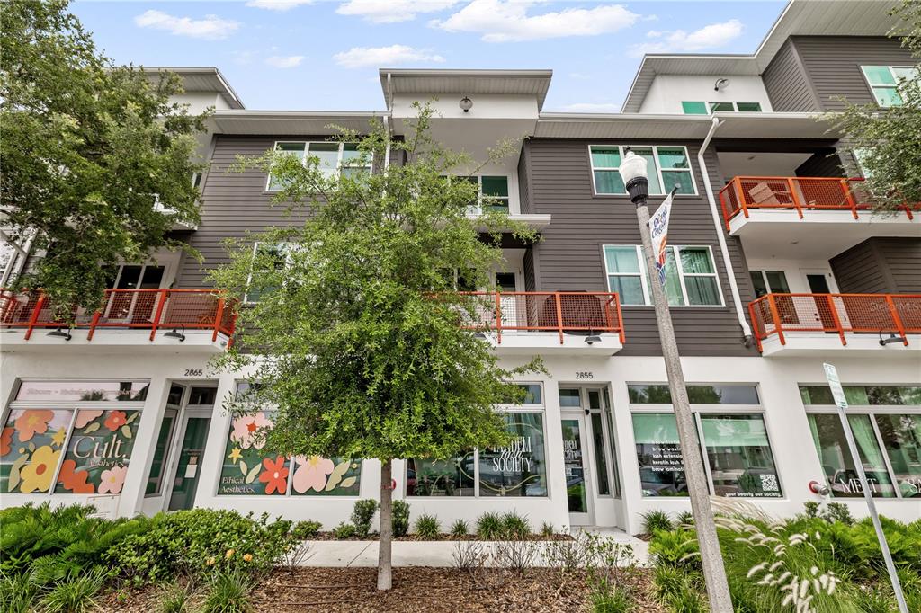 A three-story building with dark gray siding, orange railings, and ground-floor storefronts — 17 29TH STREET N Lot 8, ST PETERSBURG, FL