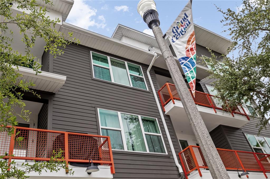 A low-angle view of a multi-story building with dark gray siding and orange metal railings — 17 29TH STREET N Lot 8, ST PETERSBURG, FL