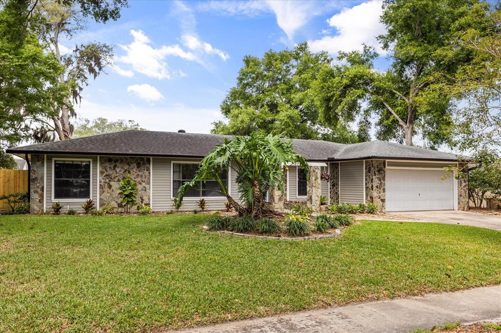 A single-story house with stone accents, horizontal siding, and a two-car garage — 817 E HARBOUR COURT, OCOEE, FL
