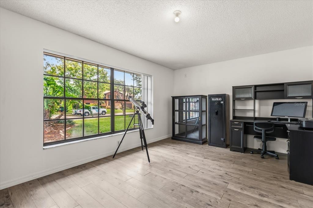 A room with light wood-look flooring, a large window, a telescope, and a black desk — 817 E HARBOUR COURT, OCOEE, FL