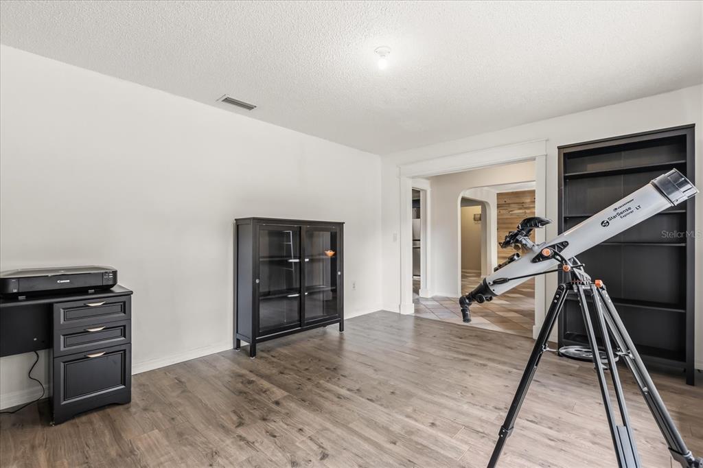 A room with wood-look flooring, a black cabinet, a printer desk, and a telescope — 817 E HARBOUR COURT, OCOEE, FL
