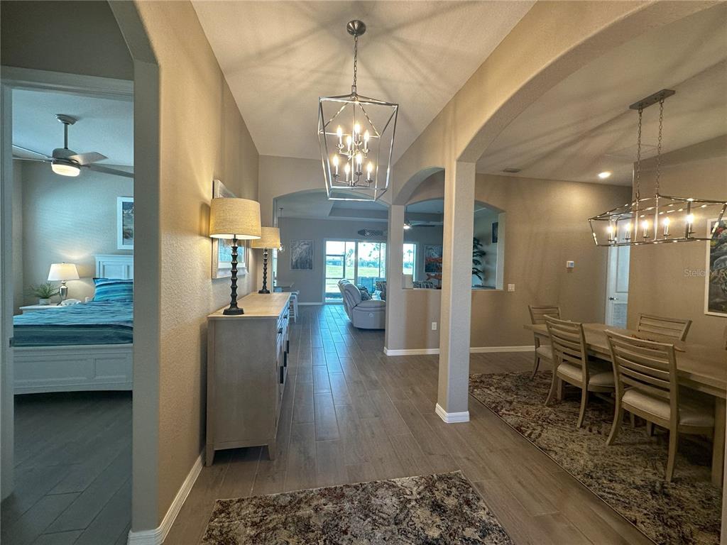 A view from a hallway looking into a dining room, bedroom, and living area — 25115 LONGMEADOW DRIVE, PUNTA GORDA, FL