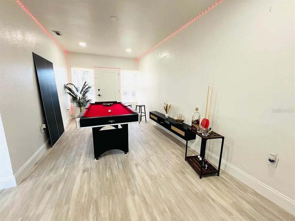A game room features a pool table, a bar cart, and light wood-look flooring — 1169 DREW STREET, CLEARWATER, FL