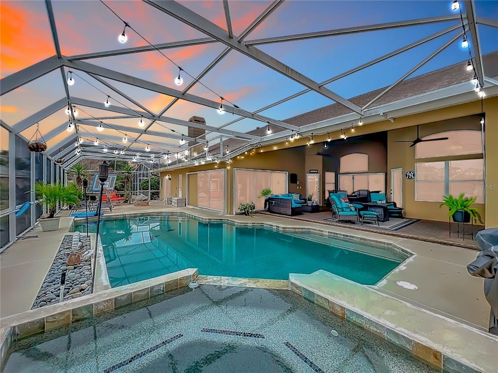 A screened-in pool and hot tub area with string lights and a covered patio — 635 CHOCKTAW STREET, LAKE MARY, FL
