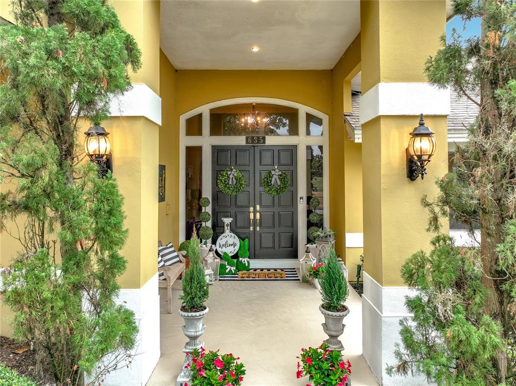 A covered entryway features yellow pillars, a dark double door with wreaths, and potted plants — 635 CHOCKTAW STREET, LAKE MARY, FL